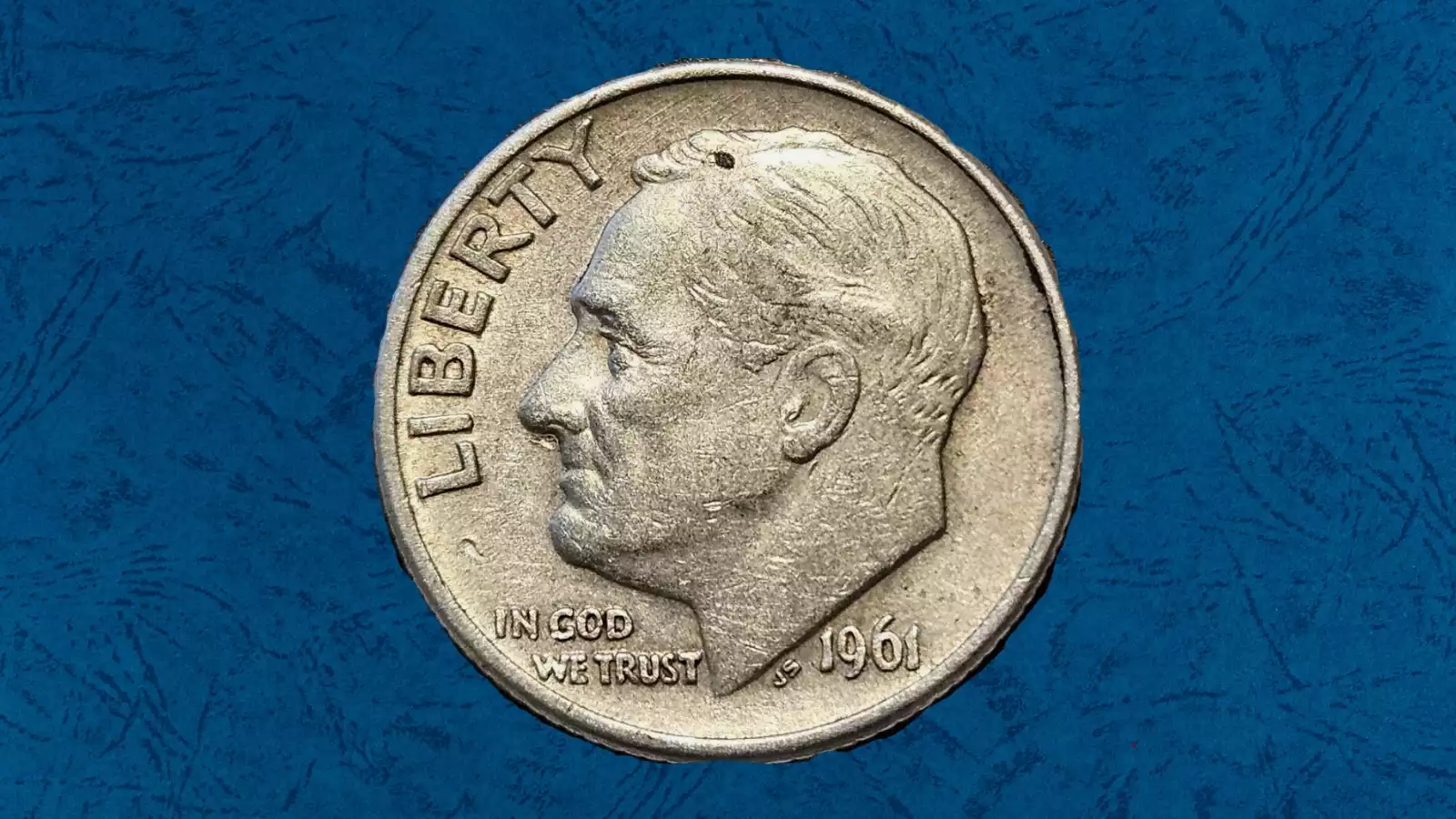 1961 Roosevelt dime die chip error showing raised metal blob on obverse, or filled die with missing letter in motto